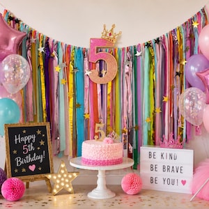May include: A festive birthday party scene with colorful decorations. Includes balloons, a cake, a sign that says "Happy 5th Birthday!", and a light-up sign that says "Be Kind Be Brave Be You!"