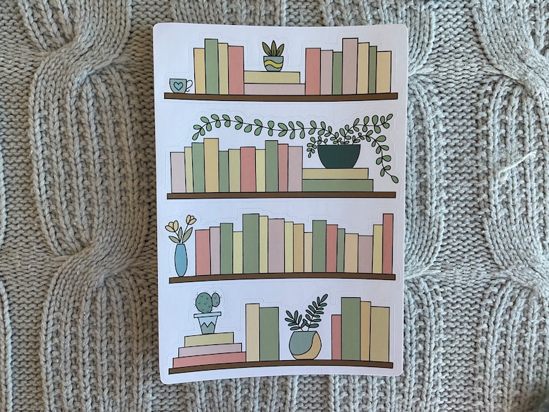 May include: Three sets of stickers featuring bookshelves with different colored books, plants, and a cup of coffee. The bookshelves are brown and the books are in shades of pink, green, yellow, and beige.