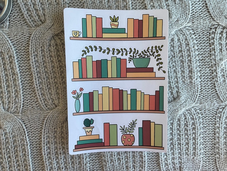 May include: A sticker sheet with four shelves of books, plants, and a cup of coffee. The shelves are white with brown trim. The books are various colors, including red, green, yellow, and brown. The plants are green and brown. The cup of coffee is white with a red heart.