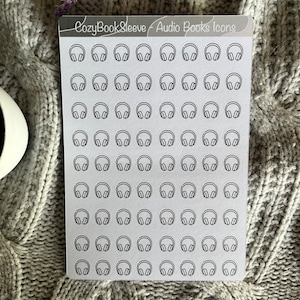 Op de afbeelding: Een vel wit stickerpapier met 64 zwart-witte koptelefoonpictogrammen. Het vel is gelabeld "CozyBookSleeve - Audio Books Icons".