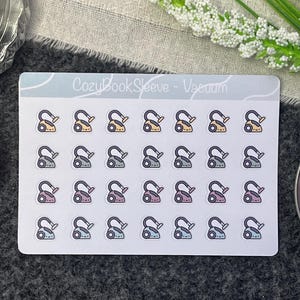 May include: A sheet of stickers featuring a variety of coloured vacuum cleaner illustrations. The stickers are arranged in a grid pattern on a white background. The text "Cozy Book Sleeve - Vacuum" is printed at the top of the sheet.