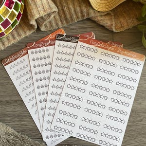 Peut inclure: Quatre feuilles d'autocollants rectangulaires étiquetées CozyBookSleeve - Star Ratings. Chaque feuille présente des rangées d'icônes en contour noir : piments, flammes et étoiles à cinq branches. Les autocollants servent à noter des livres.