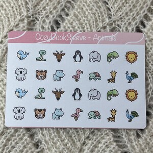 May include: A sticker sheet with the text "CozyBookSleeve - Animals" features various cartoon animal illustrations. The animals include a whale, snake, goat, penguin, elephant, chameleon, lion, koala, tiger, hippo, flamingo, turtle, giraffe, and peacock.