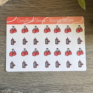 Peut inclure: Une planche d'autocollants rectangulaire avec une en-tête corail portant l'inscription CozyBookSleeve - Boxing Gloves. La planche présente quatre rangées de petites illustrations répétitives de gants de boxe rouges et de sacs de frappe gris.