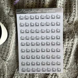 Op de afbeelding: Een vel met 60 zwarte en witte boekiconen op doorzichtige stickers. Het vel is gelabeld met "CozyBookSleeve - Book Icons".