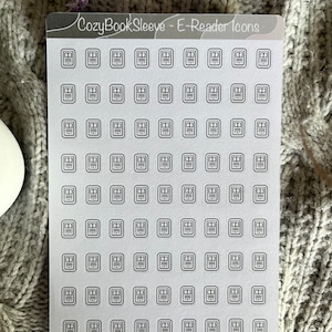 Op de afbeelding: Een vel met transparante stickers met 64 zwart-witte e-reader-pictogrammen. De pictogrammen zijn in een rasterpatroon gerangschikt en elk pictogram is een eenvoudige omtrek van een e-reader.