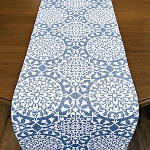 May include: A blue and white table runner with a geometric pattern. The runner is made of a linen fabric and has a subtle texture.