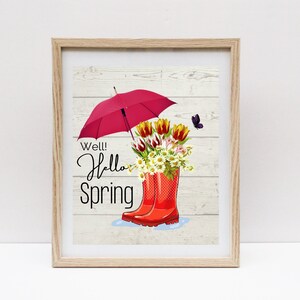 May include: A framed print with a white woodgrain background featuring a red umbrella, a bouquet of flowers in red rain boots, and the text "Well! Hello Spring".