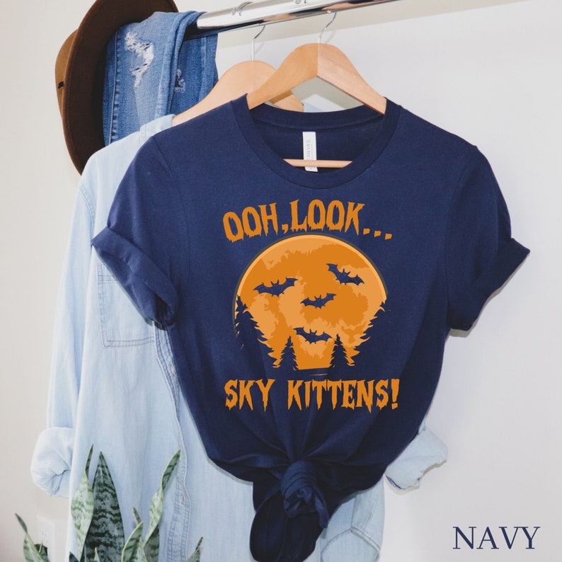 May include: A navy blue t-shirt with a graphic of a full moon and bats. The text "Ooh, look... Sky Kittens!" is printed on the shirt.