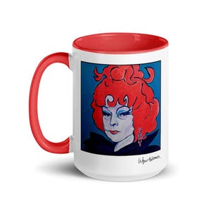 May include: White ceramic mug with a red interior and handle. The mug features a portrait of a person with red hair and blue eyeshadow against a blue background. The artist's signature is visible on the bottom right.