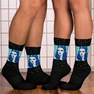 May include: A pair of black socks with a colorful image of a woman with blue hair on each sock. The socks have a black background with white stars.