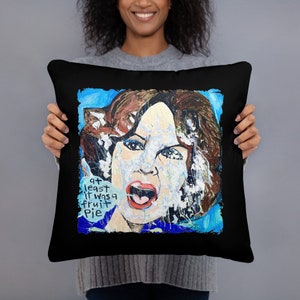 May include: Black throw pillow with a colorful painting of a woman's face with the text "at least it was a fruit pie" on the front.