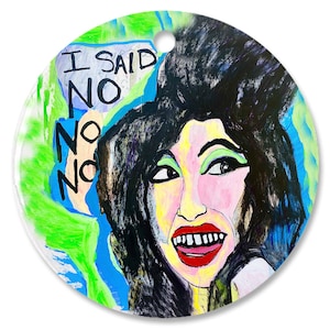 May include: A round, colorful ornament with a painting of a woman with black hair and a bright red mouth. The text "I SAID NO NO NO" is written in a white speech bubble above her head.