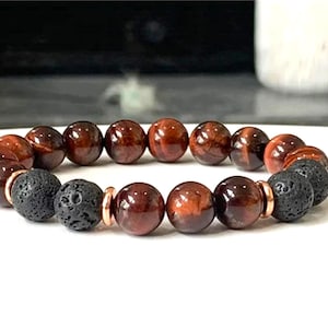 May include: A bracelet made of red tiger's eye and black lava rock beads with copper spacers.