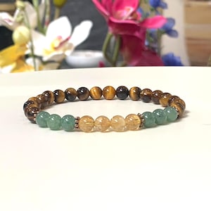 May include: A beaded bracelet featuring a sequence of brown tiger eye beads, light green aventurine beads, and translucent yellow citrine beads, accented with small metallic copper-toned spacers between the different stone sections.