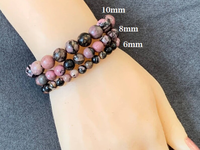 May include: Three bracelets with pink, black, and grey beads. The bracelets feature 10mm, 8mm, and 6mm beads. The bracelets are made of natural stone and are a beautiful accessory.