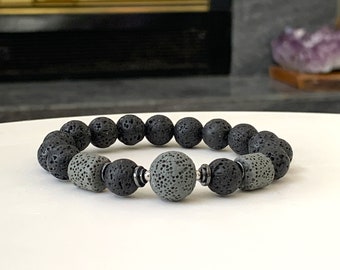 May include: A black and gray lava rock beaded bracelet with a silver spacer bead.