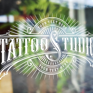 Puede incluir: Logotipo blanco de estilo vintage en una puerta de vidrio con fondo borroso. El logotipo dice "Tattoo Studio" con las palabras "Your Text Here" arriba y abajo del texto principal.