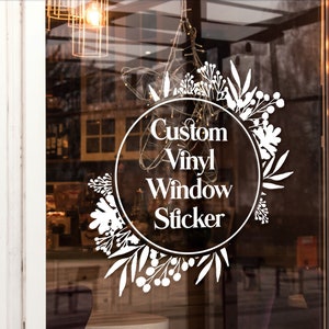 May include: White vinyl window sticker with a floral wreath design and the text "Custom Vinyl Window Sticker" in a circle.