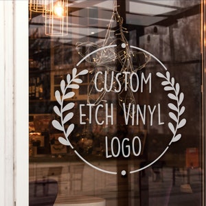 Könnte beinhalten: Ein weißer Vinyl-Aufkleber mit einem Kranz-Design und dem Text "Custom Etch Vinyl Logo" auf einer Glasvitrine.