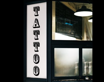 May include: A black and white sign with the word "TATTOO" in a decorative font.