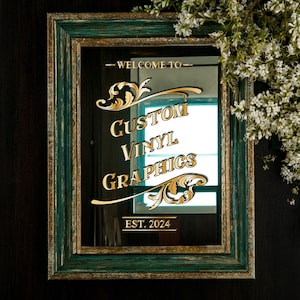 Könnte beinhalten: Ein grüner Spiegel mit goldener Beschriftung, die "Willkommen bei Custom Vinyl Graphics Est. 2024" lautet.