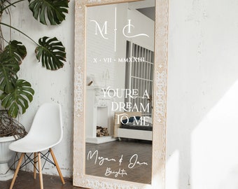 May include: A white wooden mirror with a decorative border and a white inscription that reads "You're a dream to me" and "Megan & Jan Brighton" with the date "X.VII.MMXXIII".