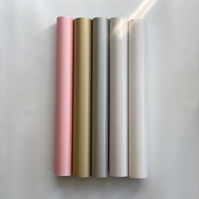 May include: Five rolls of adhesive vinyl in pink, gold, silver, white, and light gray.