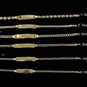 May include: A collection of six gold-toned ID bracelets, each with a different chain style and plate design. The styles include a heart-accented chain, two-tone mariner, solid two-tone curb, solid yellow curb, hollow two-tone curb, and hollow yellow curb.