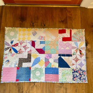 May include: A patchwork quilt with a variety of colorful fabrics and patterns. The quilt is made up of squares and rectangles, and the colors include red, blue, green, yellow, and white.