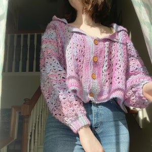 Op de afbeelding: Een paars en blauw gebreid vest met knoopsluiting. Het vest heeft een losse pasvorm en is getailleerd.