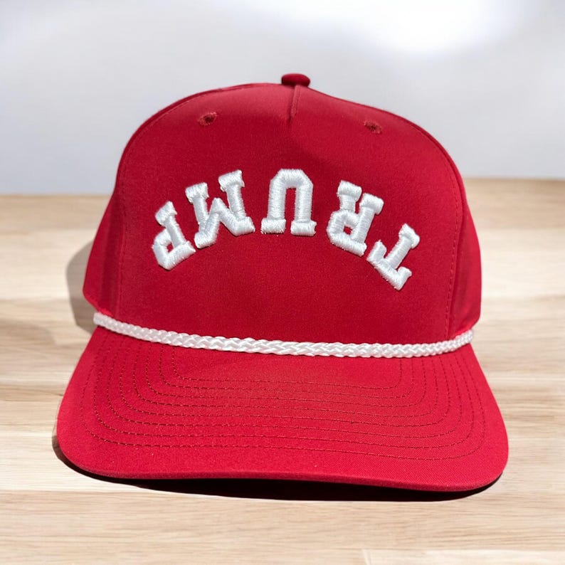May include: A red baseball cap with a white rope trim and the word "TRUMP" embroidered in white on the front.