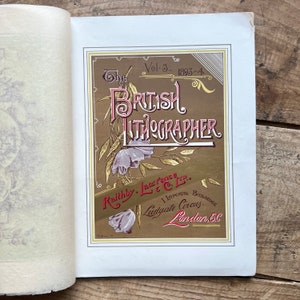 May include: A vintage book cover with a gold background and floral accents. The title "The British Lithographer" is printed in red and gold lettering. The book is published by Raithby, Lawrence & Co., Ltd. and is volume 3 from 1893-4.