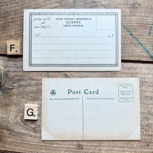 May include: Two vintage postcards. The top postcard is a light brown color with a black border and the text "UNION POSTALE UNIVERSELLE. EGYPTE CARTE POSTALE" in black. The bottom postcard is a light brown color with the text "Post Card" in green. The text "THIS SPACE FOR CORRESPONDENCE" and "THIS SPACE FOR ADDRESS ONLY" are printed in black. The text "PLACE STAMP HERE" is printed in black. The text "UNITED STATES AND CANADA, ONE CENT. FOREIGN, TWO CENTS." is printed in black.