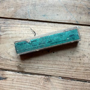 May include: A rectangular cardboard box with a teal label featuring the text Prove before laying! Point BRUSH (689) CAPS and AMERICAN TYPE FOUNDERS CO., INC. The box shows signs of wear and is positioned at a slight angle.