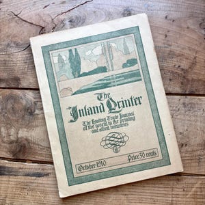 May include: A vintage October 1910 issue of The Inland Printer trade journal. The cover features a green-toned landscape illustration, decorative typography, and the text: The Leading Trade Journal of the world in the printing and allied industries.