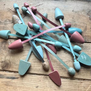 May include: A collection of vintage wooden shoe trees in shades of blue and pink. The shoe trees have metal rods that are bent into a curved shape.