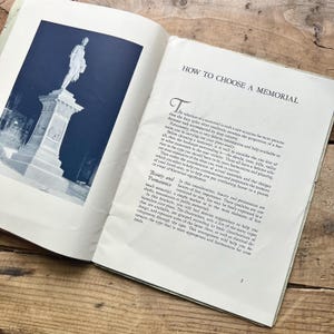 Puede incluir: Libro abierto con el t&iacute;tulo "HOW TO CHOOSE A MEMORIAL" y una imagen de una estatua. El texto trata sobre la selecci&oacute;n de un monumento, consideraciones del sitio y elecciones de materiales.