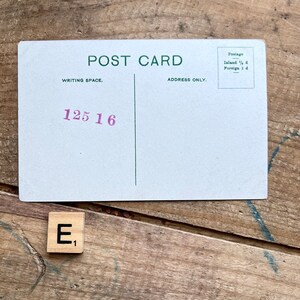 May include: A vintage postcard with a green border and the words "POST CARD" printed in green. The postcard has a writing space and an address space. The writing space has the number "125 16" printed in purple. The address space has the words "ADDRESS ONLY" printed in green. The postcard also has a postage section with the words "Postage" printed in green. The postage section has the words "Inland 1/2 d" and "Foreign 1 d" printed in black. A wooden letter tile with the letter "E" and the number "1" printed on it.