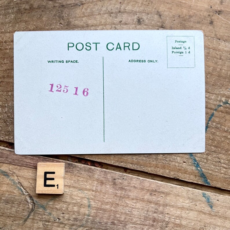 May include: A vintage postcard with a green border and the words "POST CARD" printed in green. The postcard has a writing space and an address space. The writing space has the number "125 16" printed in purple. The address space has the words "ADDRESS ONLY" printed in green. The postcard also has a postage section with the words "Postage" printed in green. The postage section has the words "Inland 1/2 d" and "Foreign 1 d" printed in black. A wooden letter tile with the letter "E" and the number "1" printed on it.