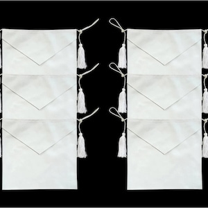 May include: Six white fabric sashes with white tassels, arranged in two rows of three. The sashes are folded in half and have a pointed flap on one side.