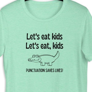 May include: A light green t-shirt with a black graphic of an alligator and the text "Let's eat kids Let's eat, kids PUNCTUATION SAVES LIVES!"