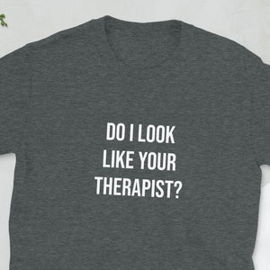 May include: Dark heather grey t-shirt with white text that reads "Do I look like your therapist?"