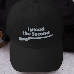 May include: A black baseball cap with a white embroidered design that says "I plead the Second" with a stylized rifle graphic.