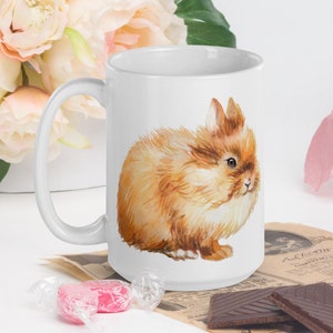 May include: White ceramic mug with a brown fluffy rabbit illustration. The rabbit is looking to the right and has a soft, watercolor-like appearance.