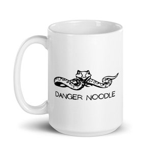 May include: White ceramic mug with a black and white illustration of a snake with the text "DANGER NOODLE" printed on the front.