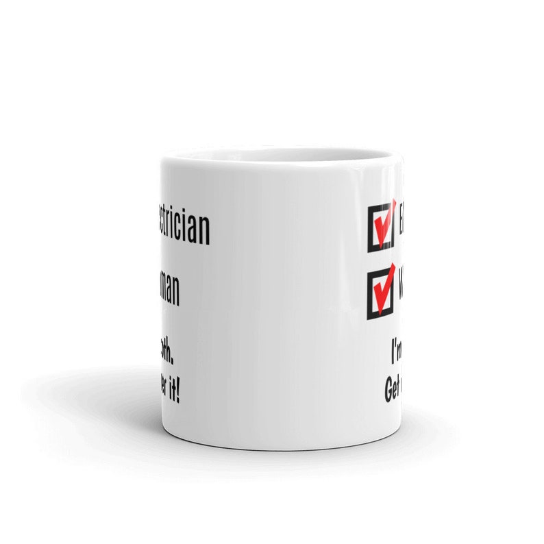 May include: White ceramic mug with black text that reads "Electrician.  I'm a wire man.  I'm with it.  Get over it!"  The mug has two red check marks next to the text "Electrician" and "Wire man".