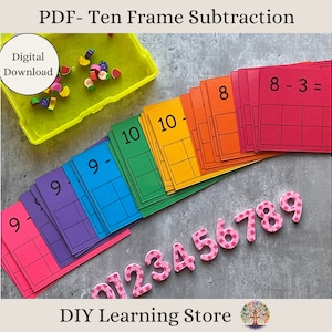 Pode incluir: Um conjunto de cartões de subtração de dez quadros com um arco-íris de cores. Os cartões são numerados de 1 a 10 e têm uma equação de subtração em cada cartão. Os cartões estão dispostos em forma de arco-íris, com o cartão vermelho no topo e o cartão verde na parte inferior. Há também números de espuma rosa de 0 a 9 e um recipiente de apagadores com forma de fruta coloridos.