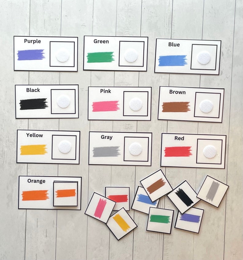 Pode incluir: Jogo de correspond&ecirc;ncia de cores com cartas que apresentam diferentes cores, incluindo roxo, verde, azul, preto, rosa, marrom, amarelo, cinza, vermelho e laranja. Cada carta tem uma amostra de cor e um c&iacute;rculo branco. Tamb&eacute;m existem cartas separadas com amostras de cor que podem ser combinadas com as cartas.