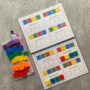 May include: A learning activity set featuring a spiral-bound book with pattern-matching exercises and a mesh bag filled with colorful square tiles. The book pages display color patterns with the text "repeat the pattern".